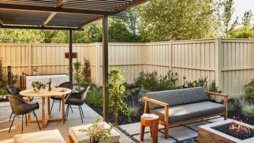 An outdoor patio area with a covered seating area, a fire pit, and a dining table with chairs.