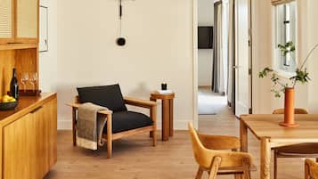 A modern kitchen with wooden cabinets, a black chair, a wooden dining table, and a hanging light fixture.