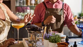 Un bar con un cantinero y un cliente, una bandeja con una bebida y granos de café, y una variedad de botellas y vasos.