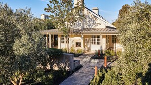 A modern house with a covered patio, surrounded by olive trees and a well-maintained garden. - Solage, Auberge Collection (Calistoga)