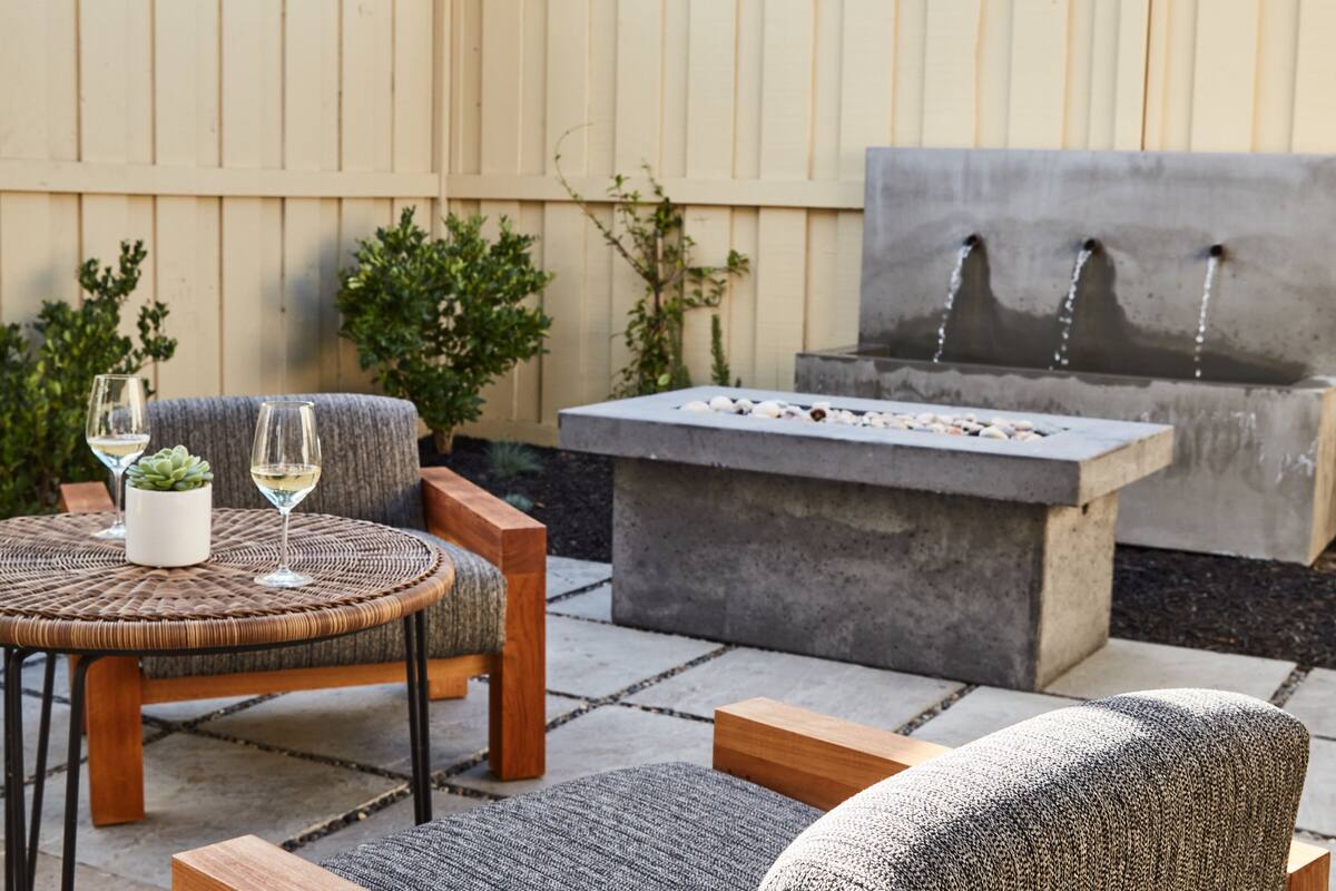 A patio area with a round table, two chairs, a small potted plant, and a built-in fire pit.