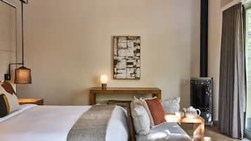 A hotel room with a bed, bedside table, lamp, artwork, and a heater.