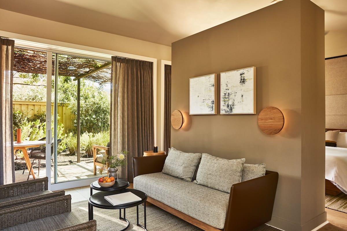 A modern living room with a sofa, a small table with a vase, and a sliding glass door leading to an outdoor area.