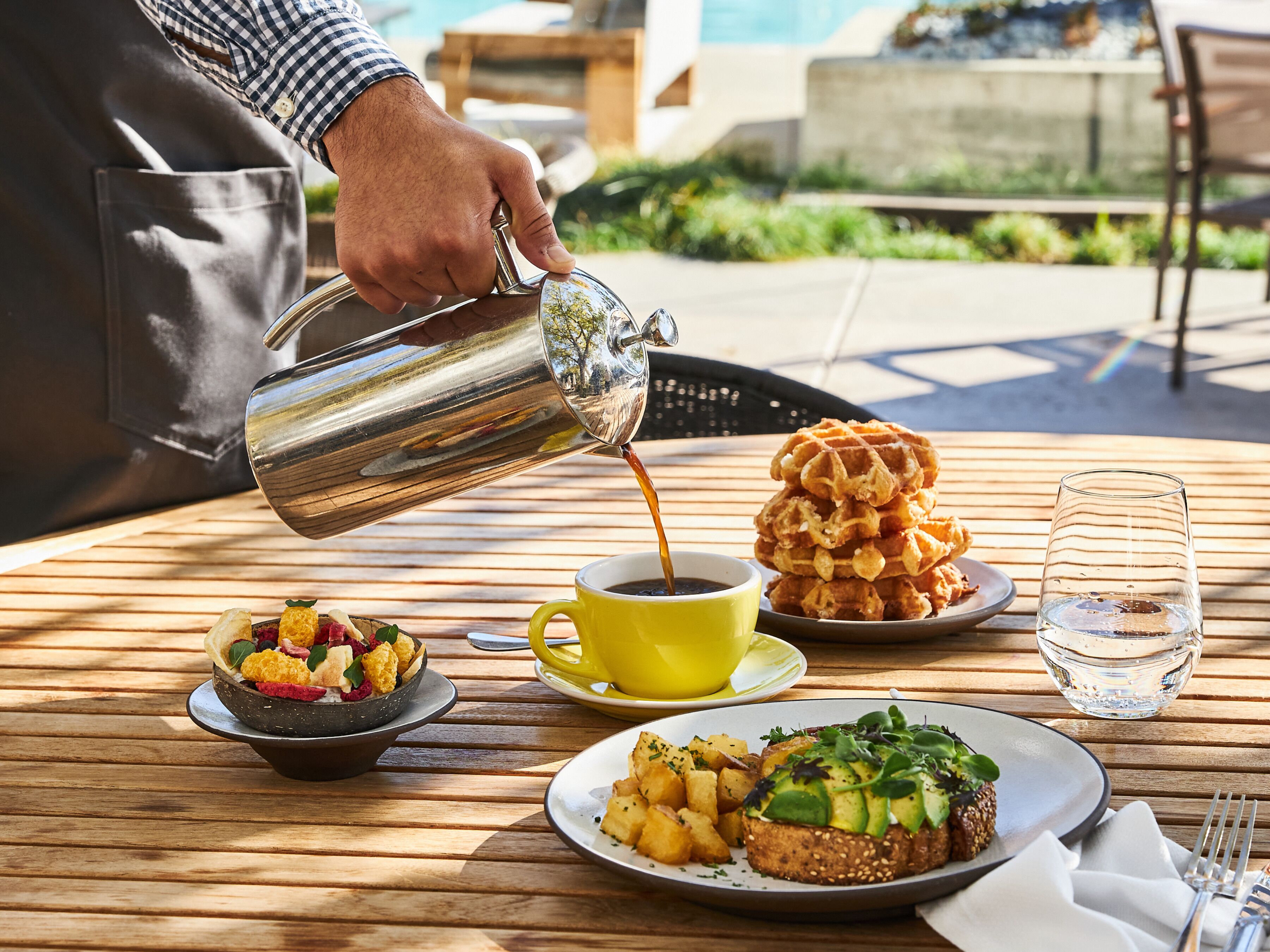 A breakfast setting with waffles, pancakes, and a cup of coffee on a wooden table.