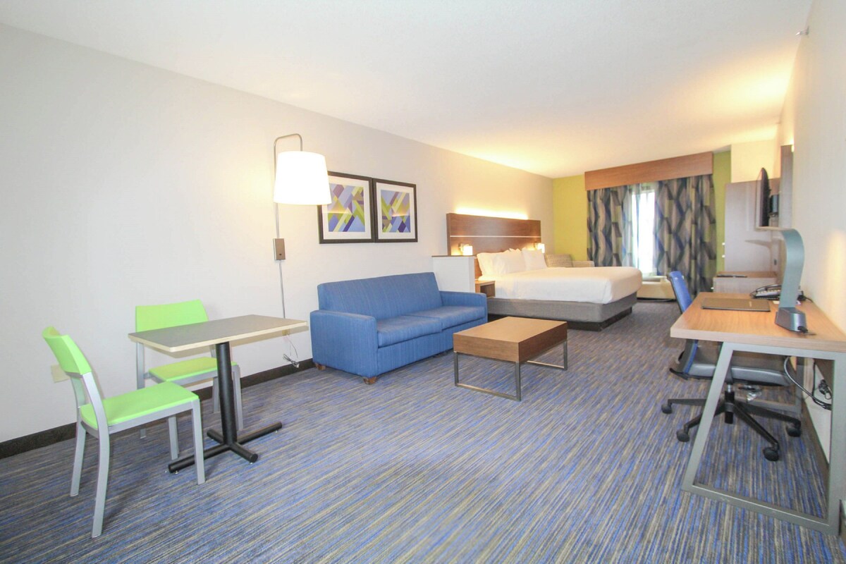 Une chambre d’hôtel avec un lit, un canapé bleu, un bureau, une chaise et une petite table.