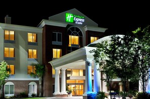 Een Holiday Inn Express & Suites gebouw met een modern ontwerp, met grote ramen en een opvallende ingang.