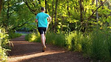 A person running on a dirt path surrounded by greenery.
