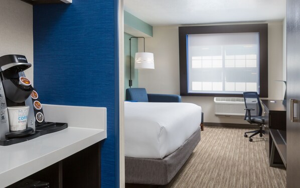 A hotel room with a bed, a desk, a coffee machine, and a window with blinds. - Holiday Inn Express Hotel & Suites Eugene Downtown-University by IHG (Eugene)
