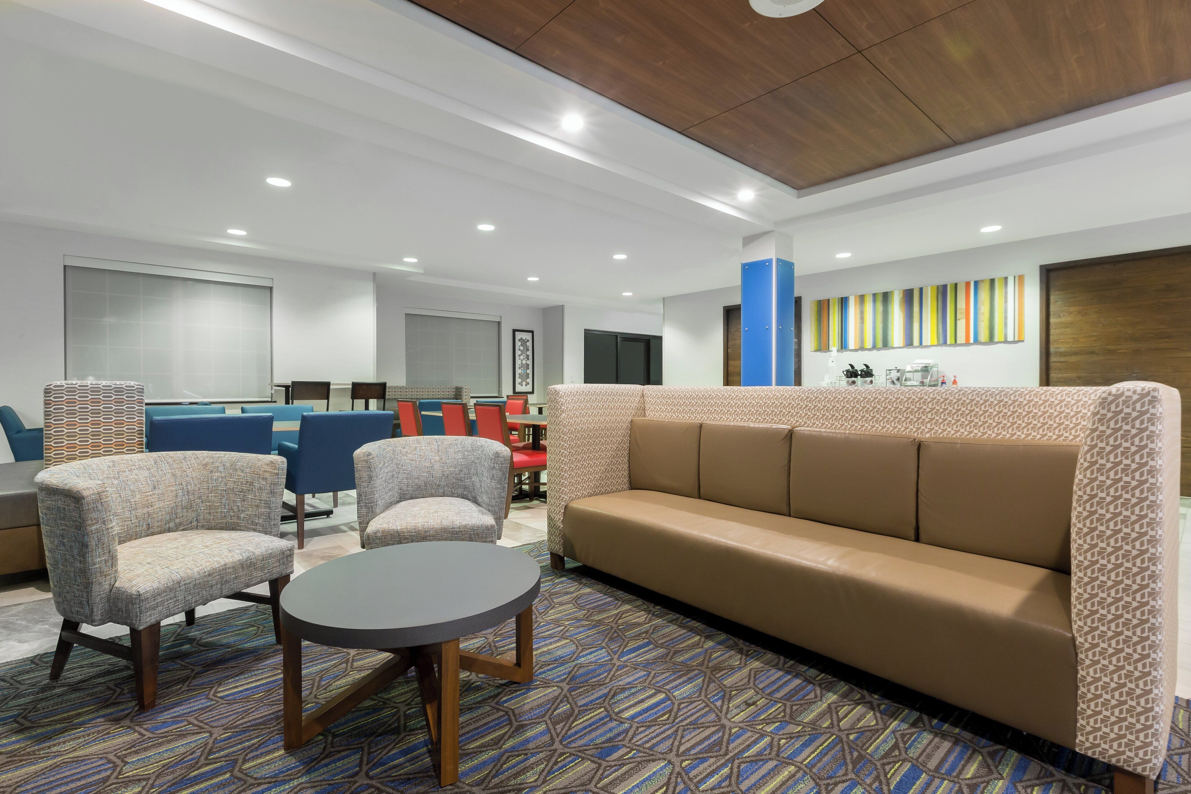 Un hall d’entrée moderne avec un canapé, des fauteuils, une table ronde et un coin repas avec des chaises.