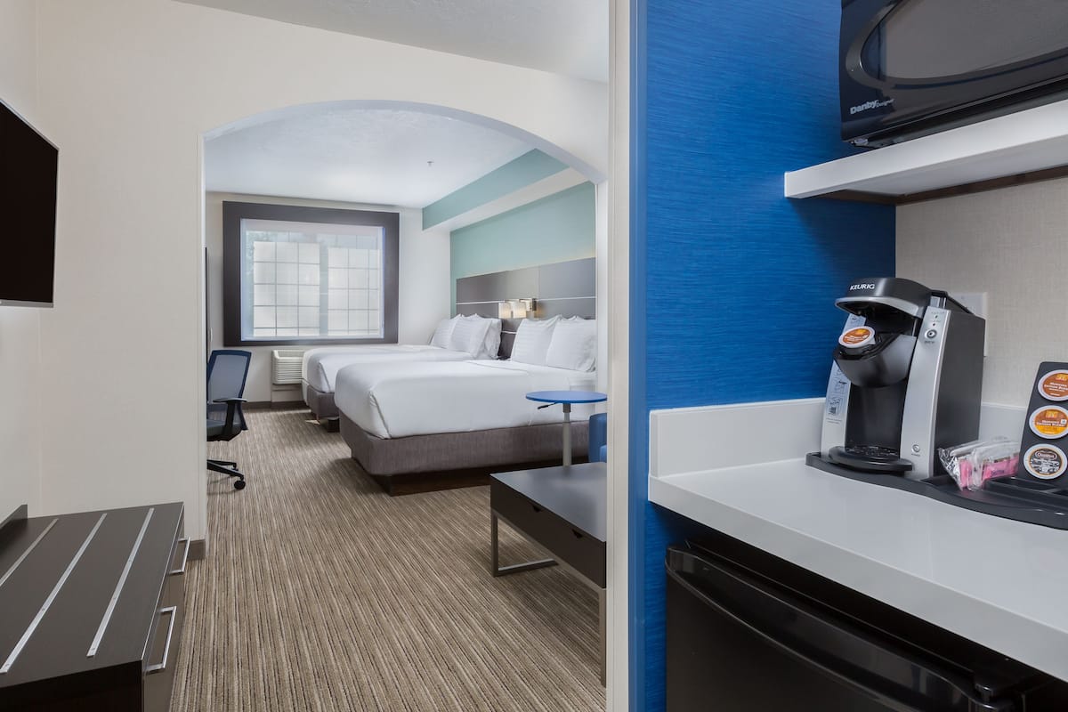 A hotel room with a bed, a desk, a coffee machine, and a television.