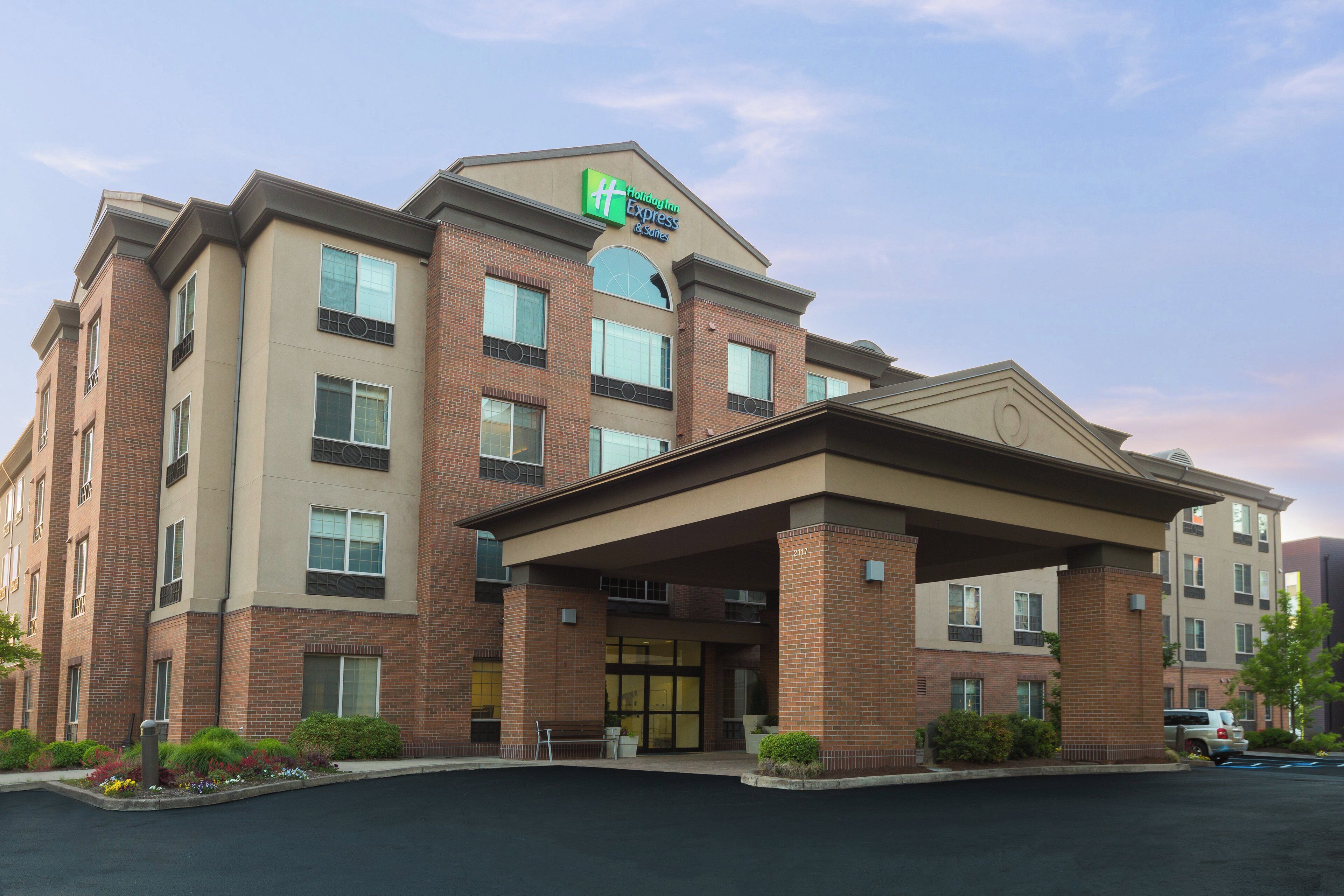 A Holiday Inn Express & Suites building with a brick facade, multiple windows, and a covered entrance.