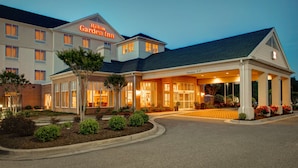 Ein Hotel mit freiem Zugang, einer Beschilderung mit dem Schriftzug "Hilton Garden Inn" und einem überdachten Parkbereich.