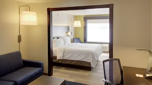 Una habitación de hotel con cama, escritorio, silla, sofá y lámpara.