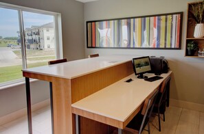 A modern office space with a desk, computer, and a large window.