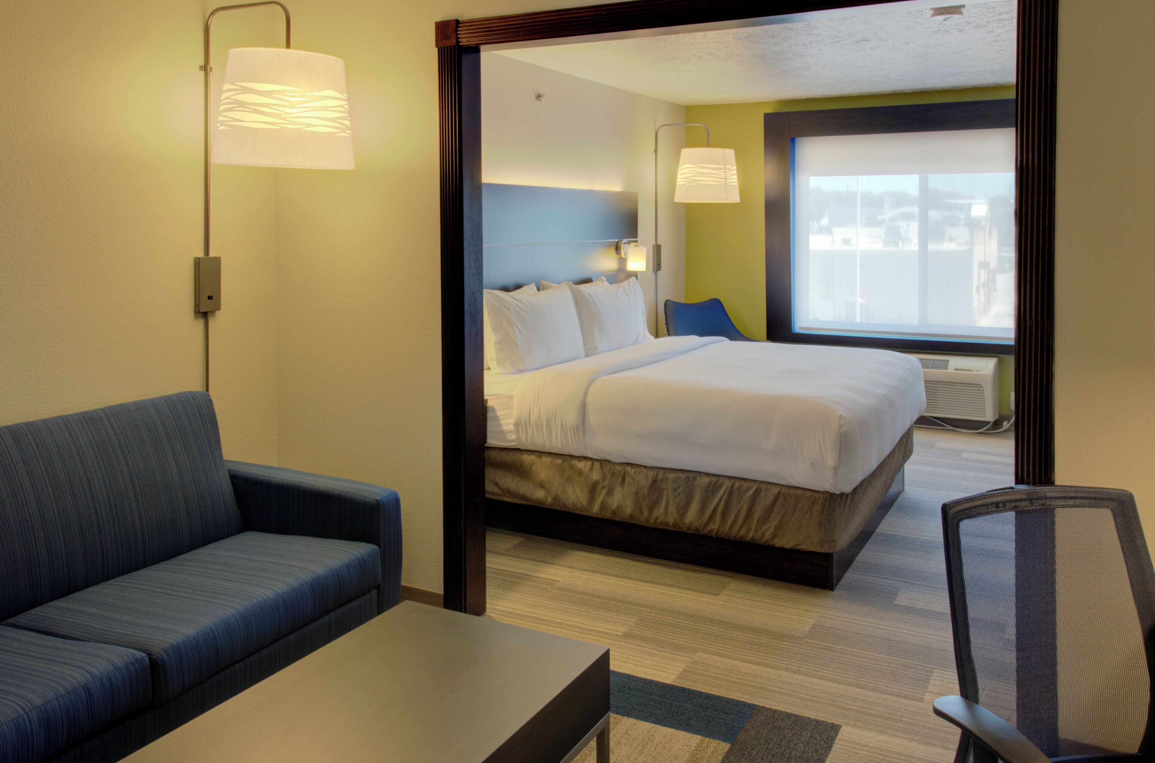 Una habitación de hotel con cama, sofá, escritorio y una silla.