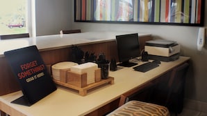 Un escritorio moderno de oficina con una computadora, teclado y un letrero que dice '¿Olvidaste algo? ¡Tómatelo aquí!'