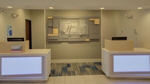 Un área de recepción con diseño moderno, que incluye una pantalla digital grande y un mostrador de recepción.