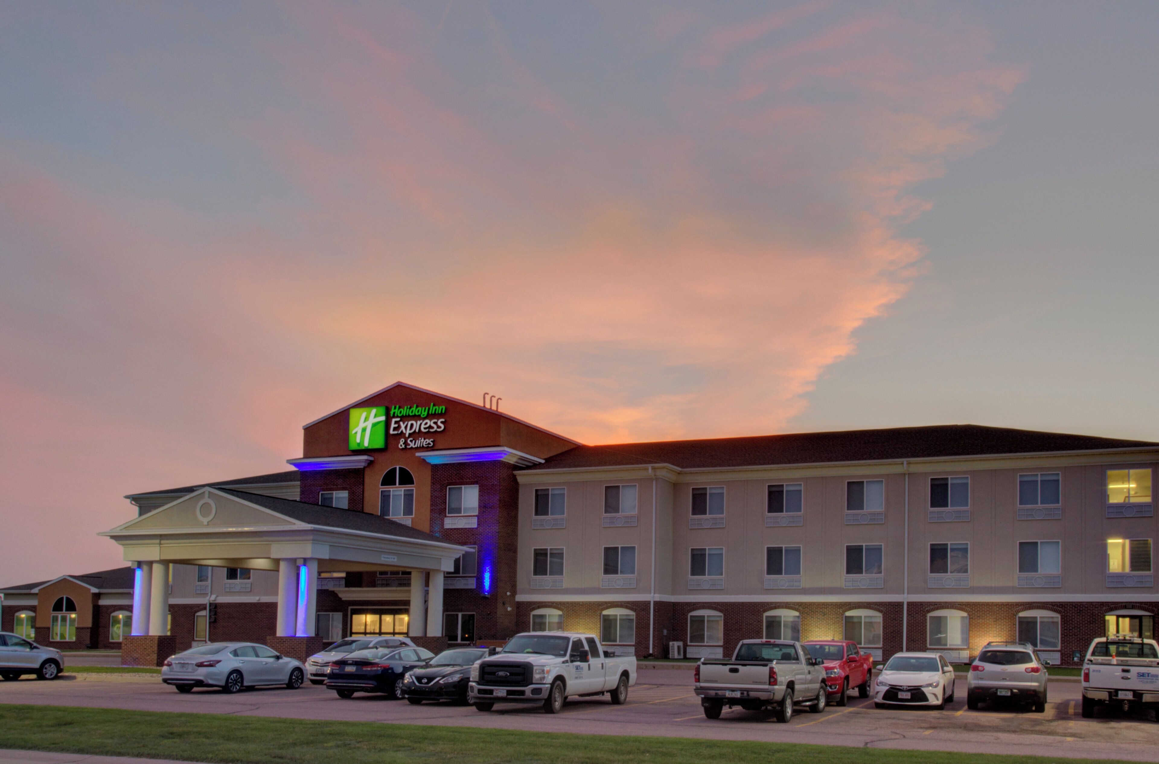 A Holiday Inn Express & Suites hotel with a parking lot full of cars.
