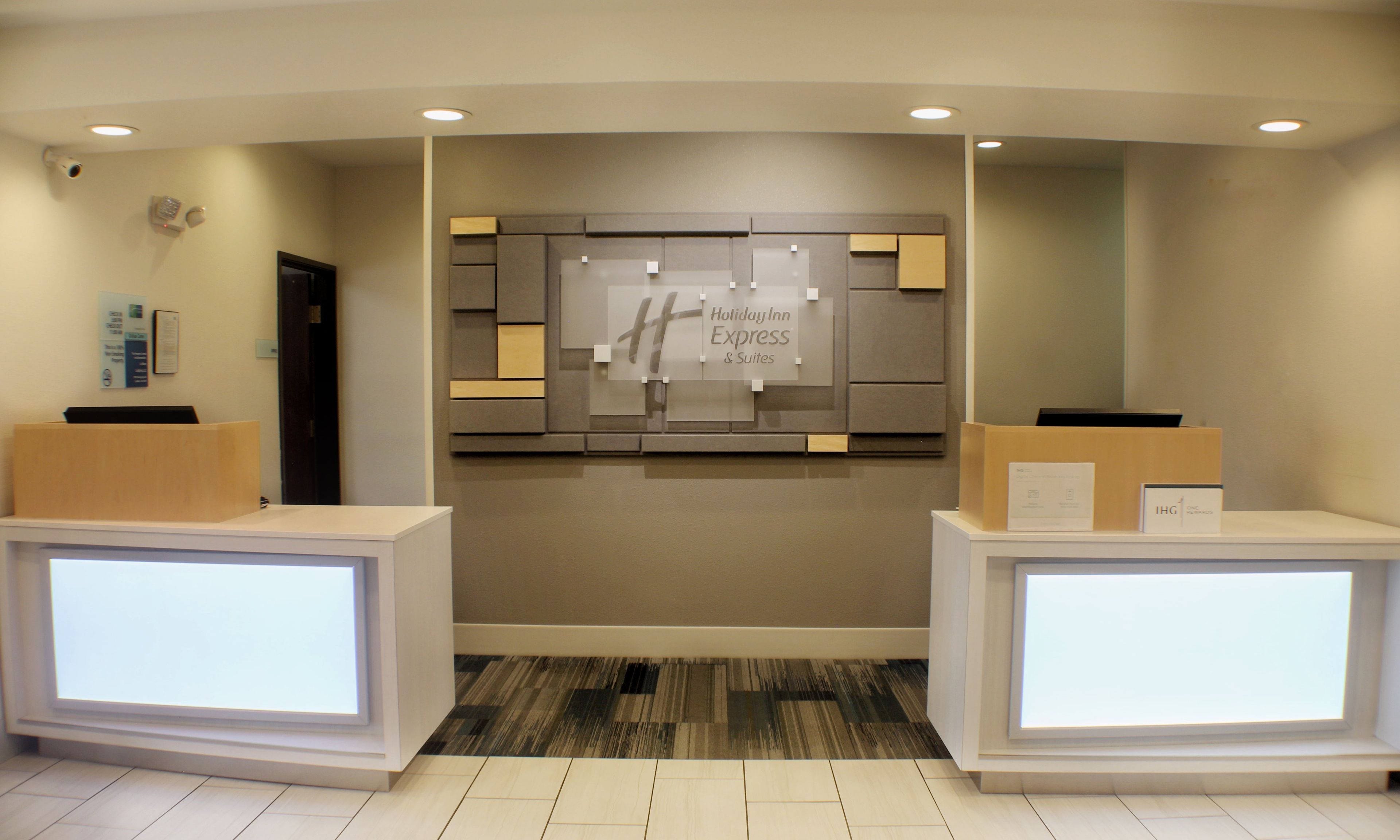 A reception area with a Holiday Inn Express sign, a reception desk, and a wall-mounted information board.