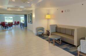 A hotel lobby with a reception desk, a sofa, chairs, and a dining area with tables and chairs. - Holiday Inn Express Hotel & Suites Le Mars by IHG (Le Mars)