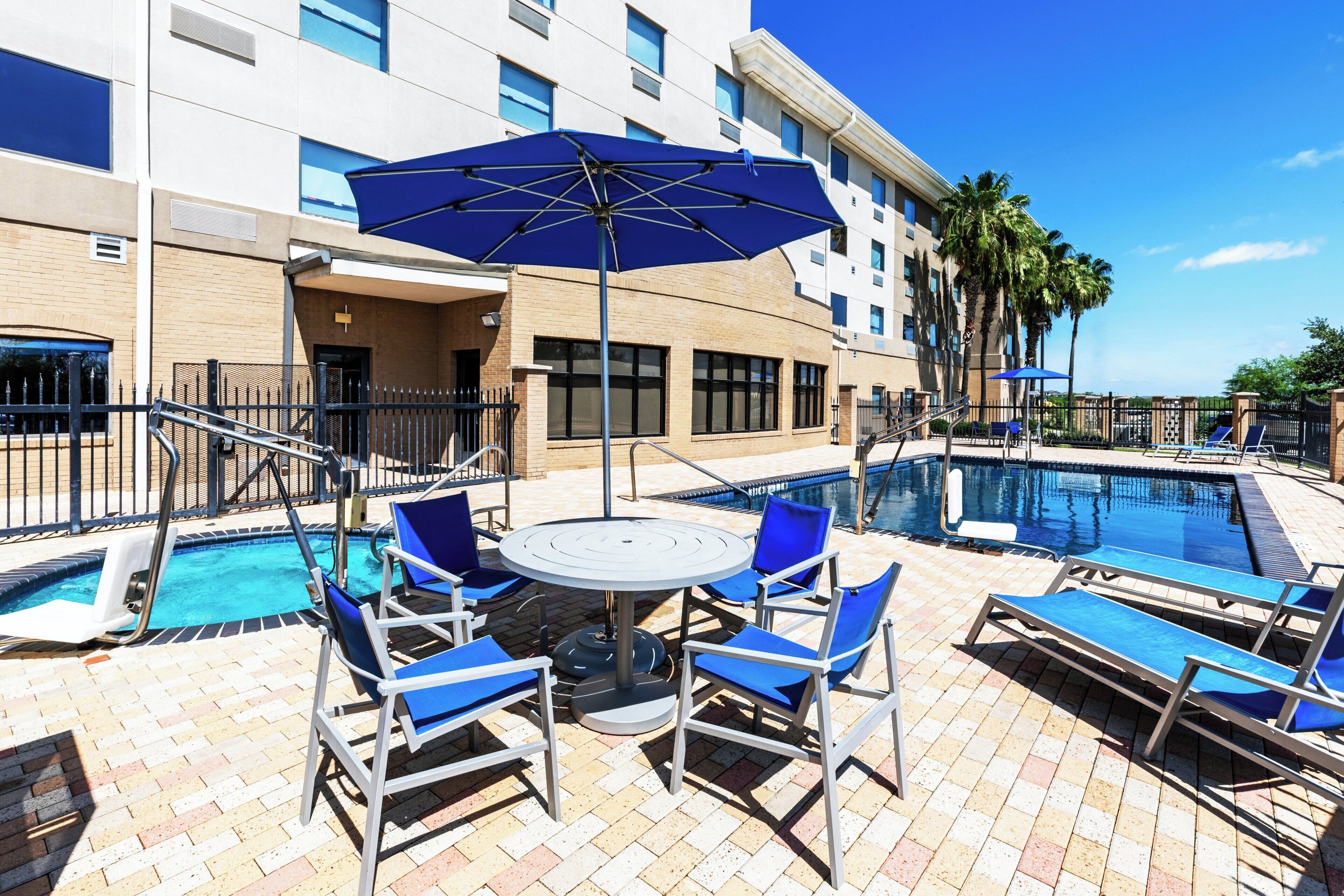 A poolside area with lounge chairs, a table, and umbrellas.