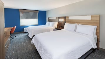 A hotel room with two beds, a desk, a chair, and a window.
