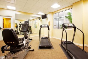 Un gimnasio con cintas de correr, elípticas y equipo de ejercicio.