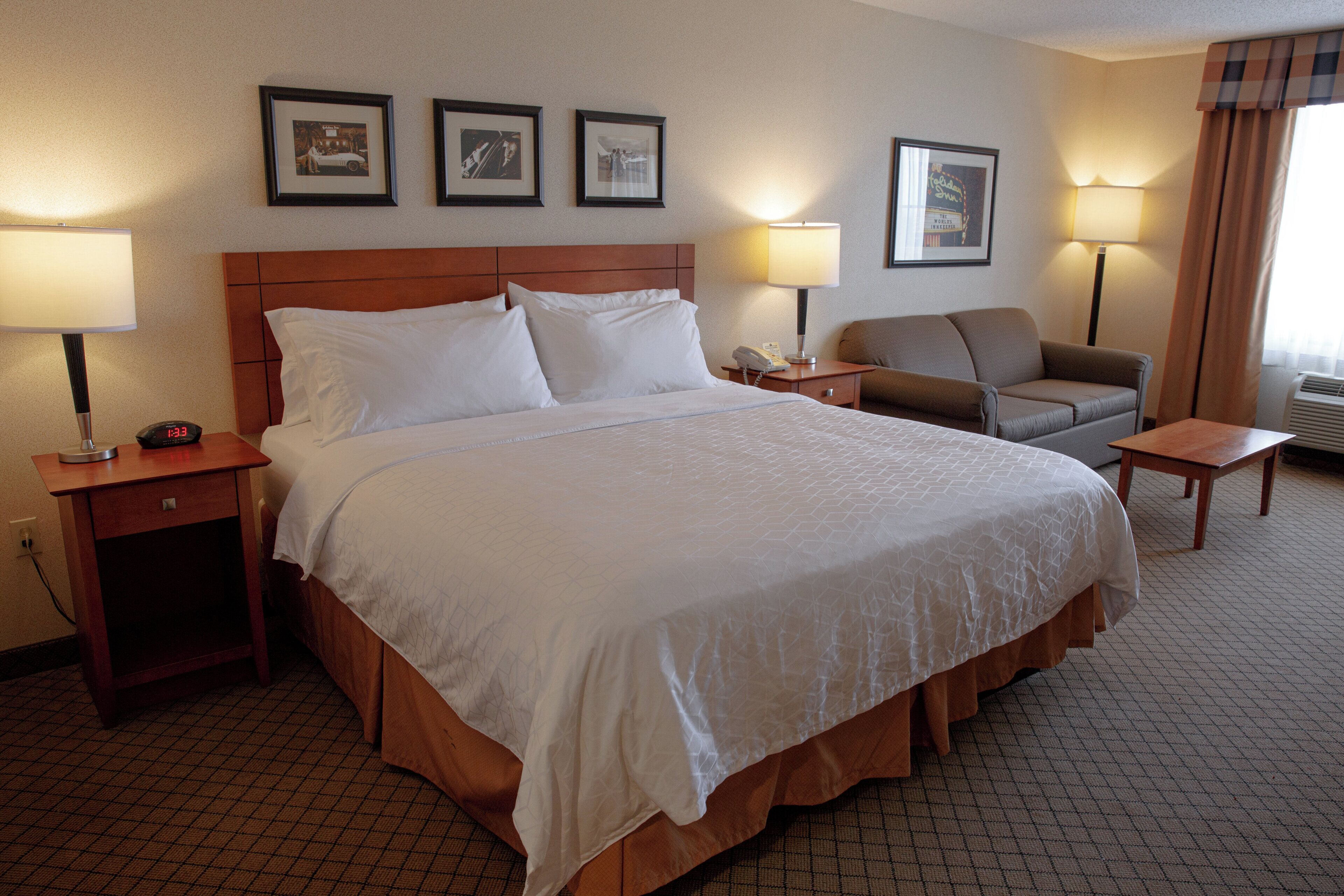 A hotel room with a large bed, a nightstand, a desk, a chair, and two lamps.