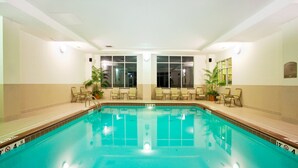 An indoor swimming pool with clear water, surrounded by lounge chairs and potted plants. - Holiday Inn Battle Creek by IHG (Battle Creek)