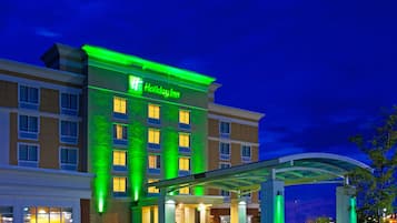 A Holiday Inn hotel with a modern facade, illuminated signage, and a covered entrance area.