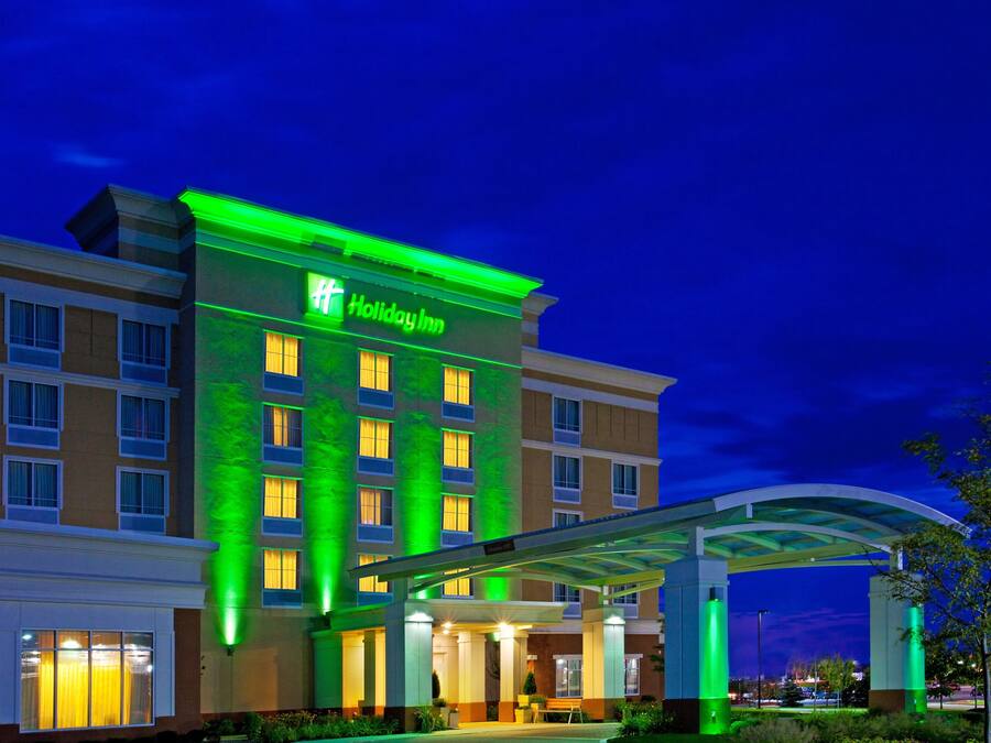 A Holiday Inn hotel with a modern facade, illuminated signage, and a covered entrance area.