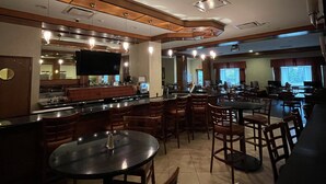 A restaurant with a bar area, multiple tables, and chairs. - Holiday Inn Battle Creek by IHG (Battle Creek)