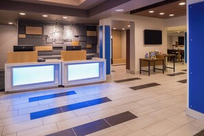 A reception area with a modern design, featuring a reception desk with a digital display, a seating area with a table and chairs, and a wall-mounted television. - Holiday Inn Express Sierra Vista by IHG (Sierra Vista)