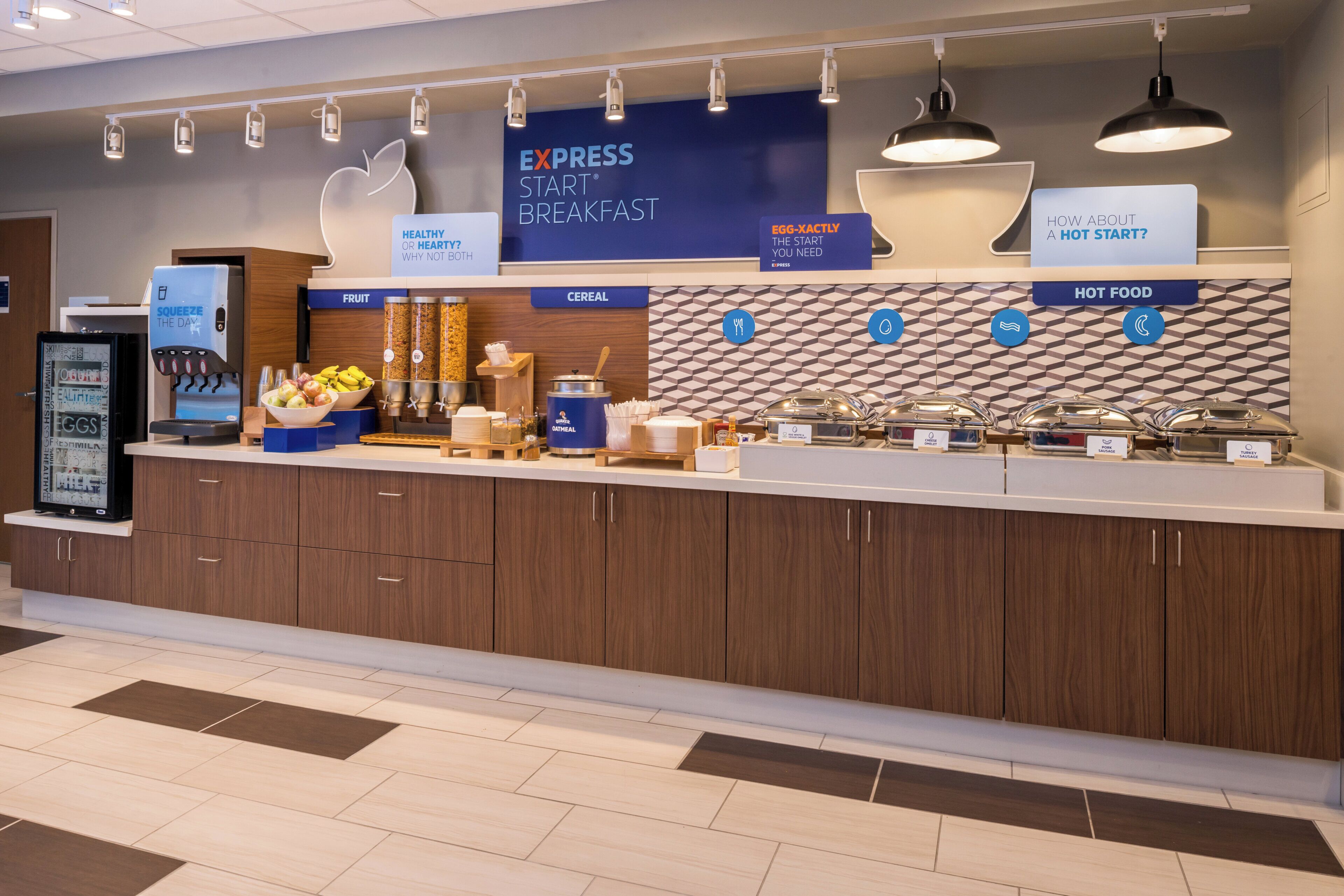A breakfast buffet area with labeled sections for fruit, cereal, and hot food.