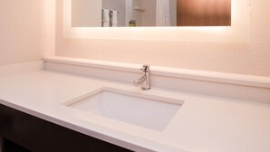 Ein Badezimmer mit einem weißen Waschbecken, einem Spiegel und einem Handtuchhalter.
