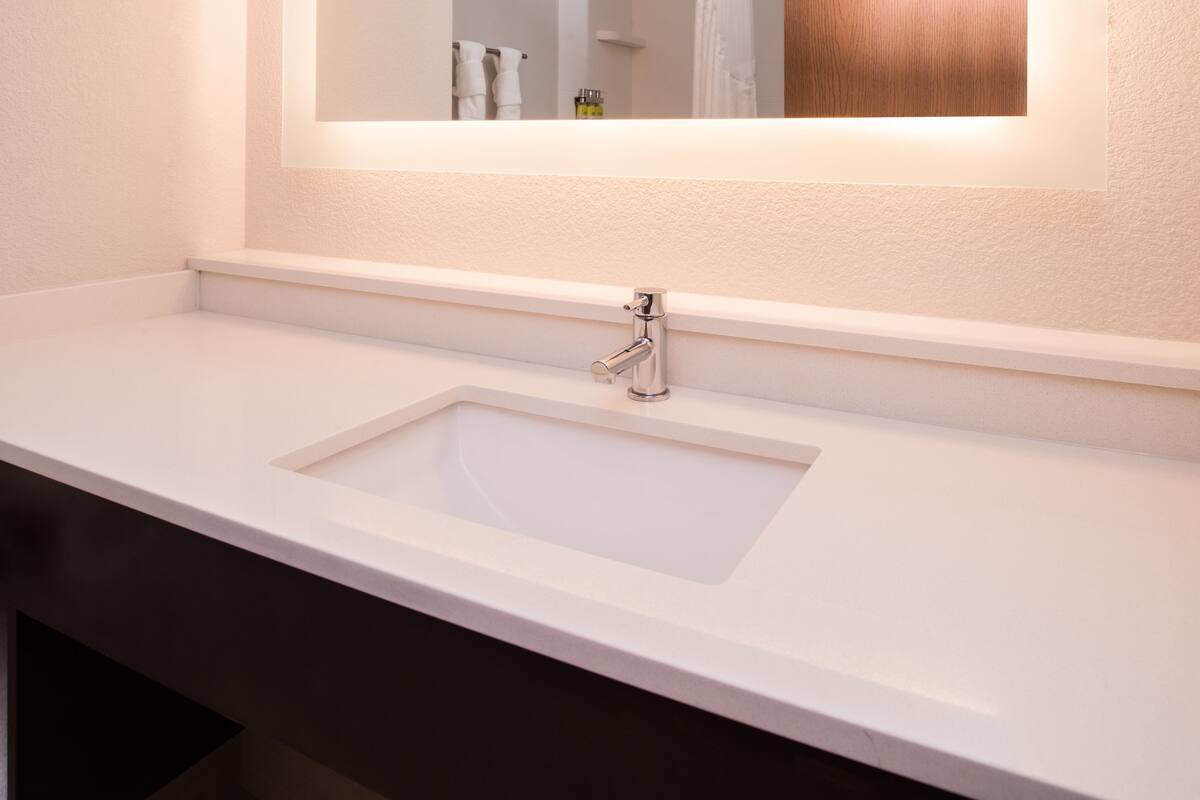 A bathroom with a white sink, a mirror, and a towel rack.