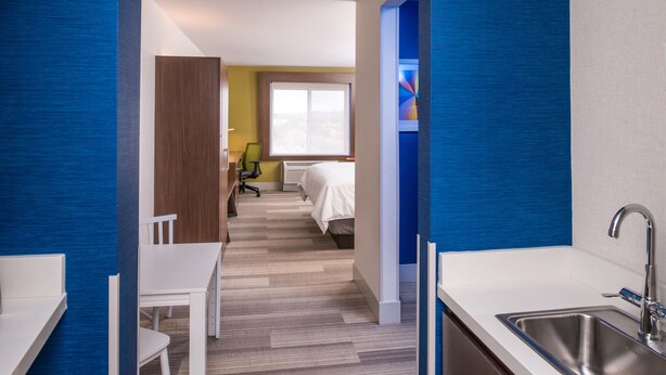Ein Hotelzimmer mit Bett, Schreibtisch und Stuhl. Ein Fenster bietet Blick auf die Stadt.