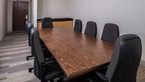 Una sala de conferències amb una taula de fusta llarga i sis cadires de malla negra.