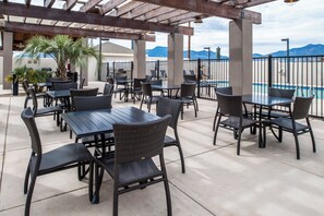 An outdoor patio area with tables and chairs, a pool, and mountains in the background. - Holiday Inn Express Sierra Vista by IHG (Sierra Vista)