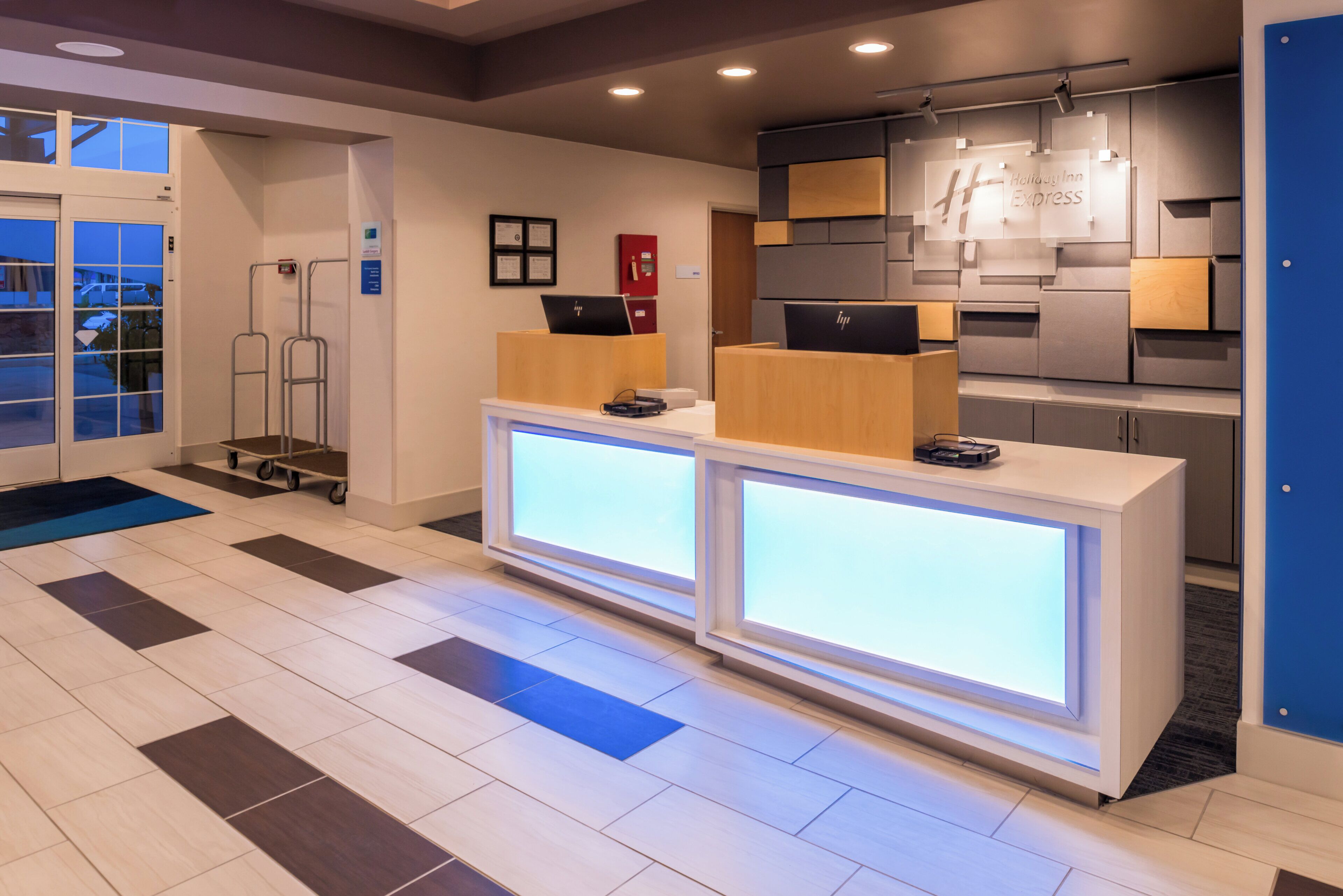 Een receptiebalie met een digitaal scherm, een brandblusser en een bord met Holiday Inn Express.
