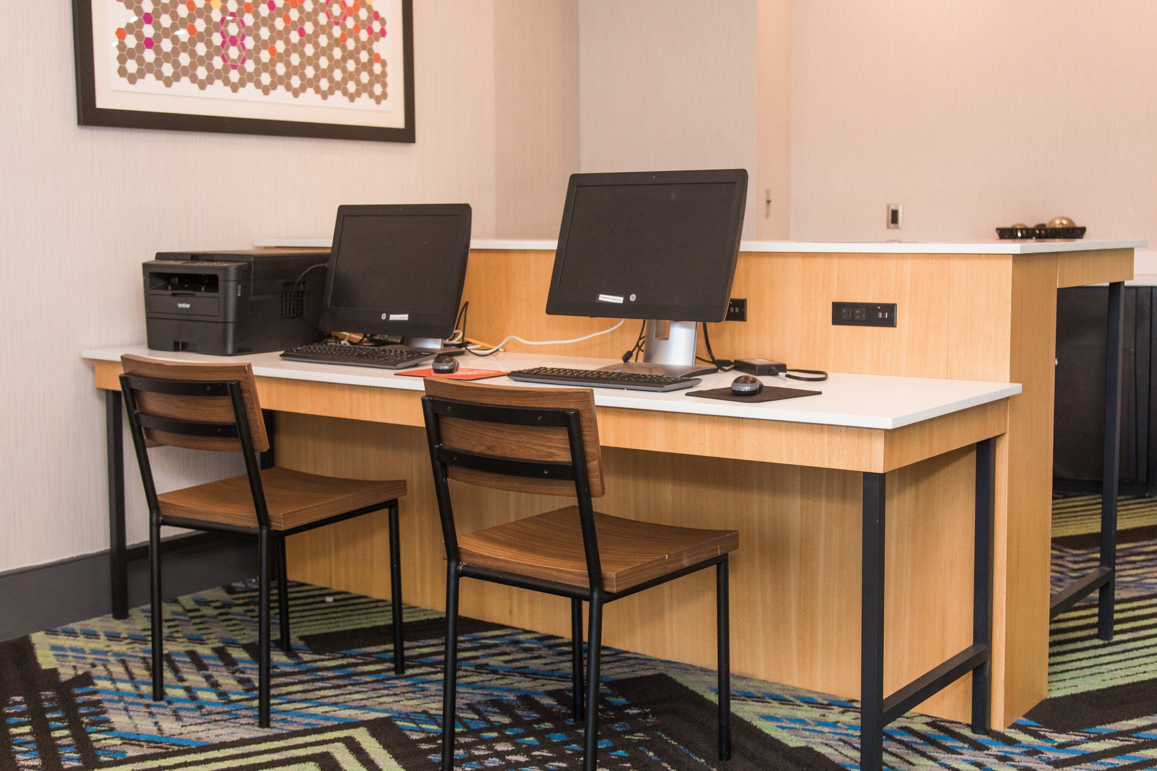 A workspace with two desktop computers, a printer, and two chairs.