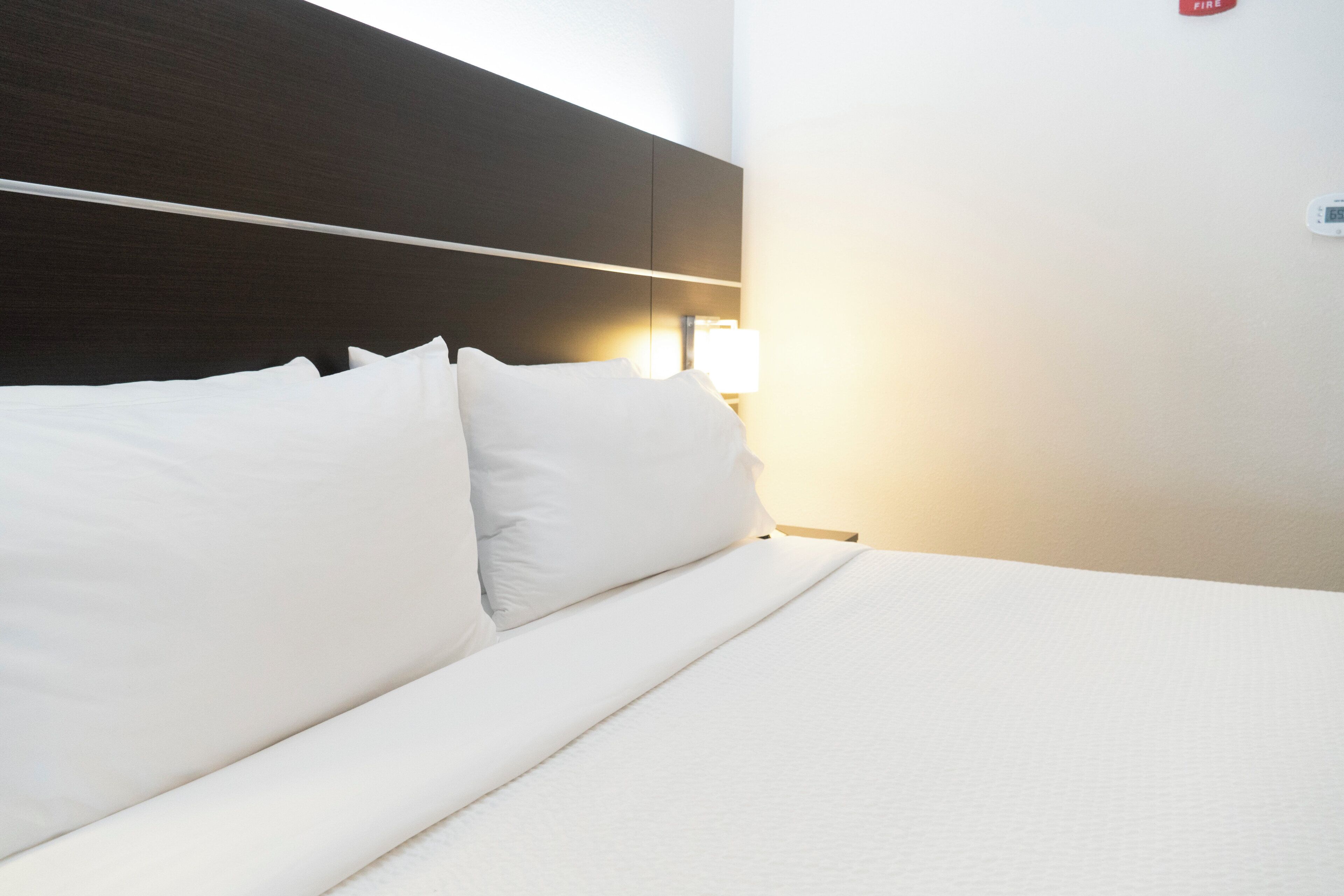 Una cama bien tendida con sábanas blancas en una habitación de hotel.