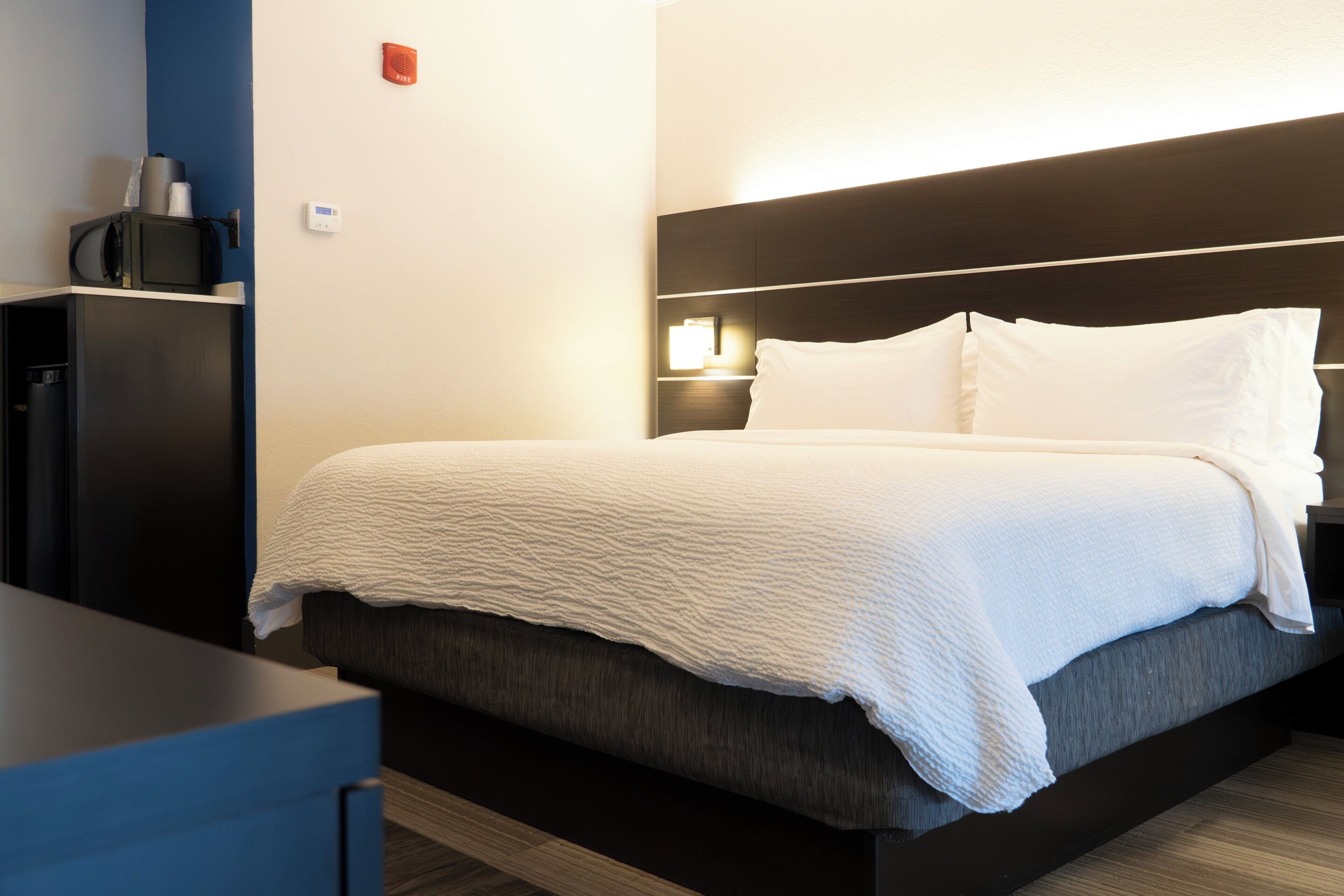 Een hotelkamer met een bed, nachtkastje en een klein kastje.