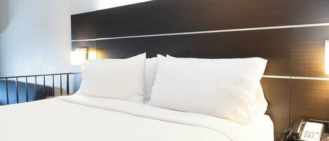 Una habitación de hotel con una cama, un teléfono junto a la cama y dos lámparas de pared.