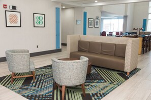 A modern lounge area with a brown sofa, two patterned armchairs, and a patterned rug. - Holiday Inn Express & Suites Columbia-Fort Jackson by IHG (Columbia)