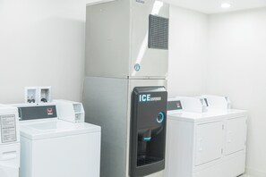 A laundry facility with a large industrial ice dispenser, a washing machine, and a dryer. - Holiday Inn Express & Suites Columbia-Fort Jackson by IHG (Columbia)