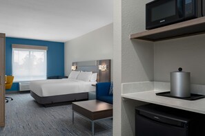 A hotel room with a bed, bedside table, chair, microwave, and a small kitchen area with a microwave and a kettle. - Holiday Inn Express & Suites Alexandria by IHG (Alexandria)