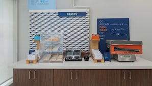 A bakery counter with a clear display case, a coffee maker, and a flat-top griddle for pancakes.