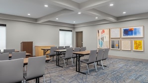 A conference room with tables and chairs, a podium, and artwork on the walls.