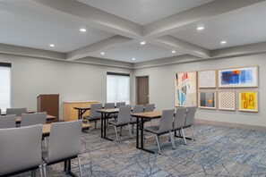 Un salón de conferencias con mesas y sillas, un atril y obras de arte en las paredes.